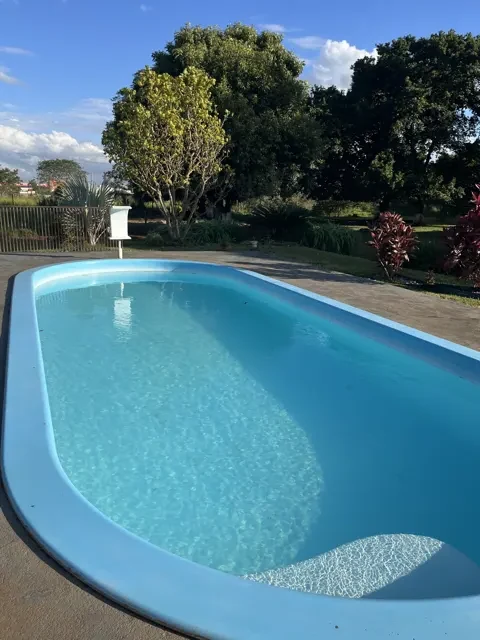 A piscina de água azul e clara, com árvores em volta